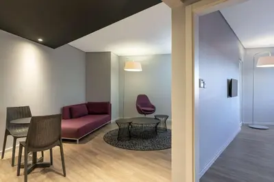 a waiting room with a red couch and tables and chairs at Park Inn by Radisson Polokwane in Polokwane