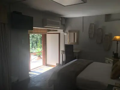 a bedroom with a bed and an open window at Windmills Rest in Pretoria