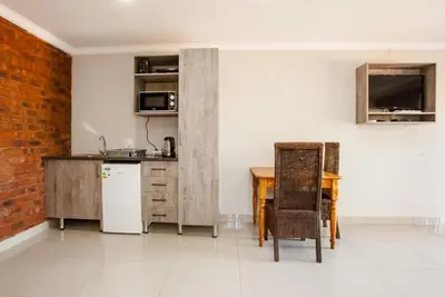 a kitchen with a table and a white refrigerator at Windmills Rest in Pretoria