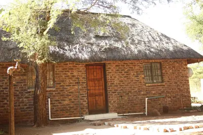 a small brick house with a thatched roof at Roundhouse Marloth Park in Marloth Park