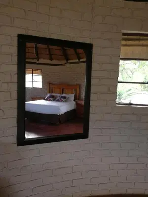 a mirror on a wall with a bed in a room at Roundhouse Marloth Park in Marloth Park