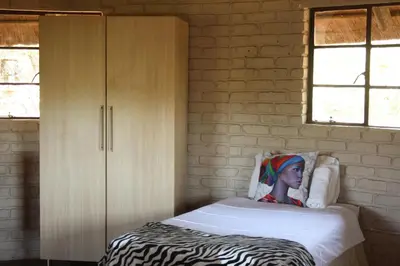 a small bedroom with a bed and a cabinet at Roundhouse Marloth Park in Marloth Park