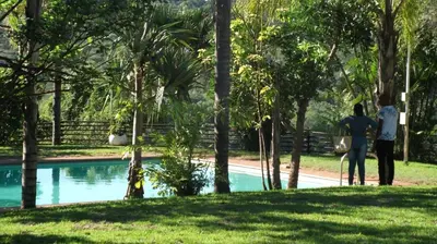 two people standing next to a swimming pool at Eagles Nest Chalets in Hazyview