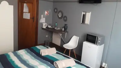 a bedroom with a bed and a chair and a television at Lallapanzi Country Stay in Ermelo