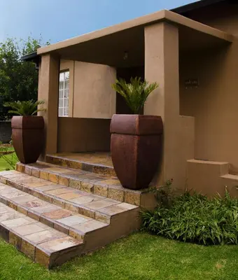 a house with two large flower pots on the stairs at Lallapanzi Country Stay in Ermelo