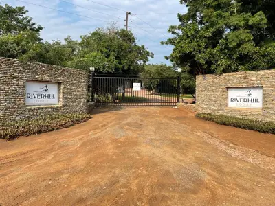 a gate in a brick wall with a driveway at River Hill Lodge in Komatipoort