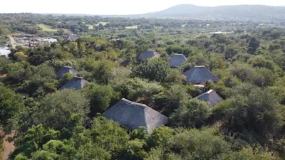 an aerial view of a village with trees and huts at River Hill Lodge in Komatipoort