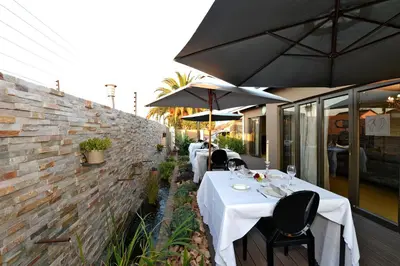 a restaurant with tables and umbrellas on a patio at Kgarebana Boutique Guesthouse in Tweefontein