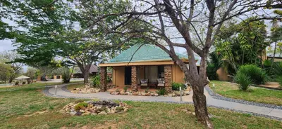 a small house with a green roof in a park at Motlala Game Lodge in Hoedspruit