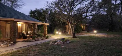 a house with lights in the yard at night at Motlala Game Lodge in Hoedspruit