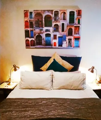 a bedroom with a bed with a painting on the wall at Adorable Designs in Pretoria