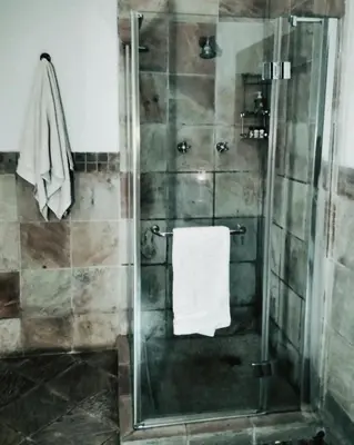 a bathroom with a shower with a white towel at Adorable Designs in Pretoria