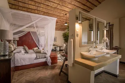 a bedroom with a bed and a sink and a mirror at Karongwe - Becks Safari Lodge in Hoedspruit