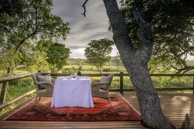a table and chairs on a deck with a tree at Karongwe - Becks Safari Lodge in Hoedspruit