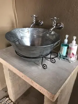 a metal sink with a faucet on top of a table at White Linen Guesthouse in Tierpoort
