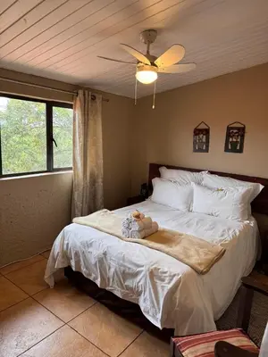 a bedroom with a large white bed with a fan at White Linen Guesthouse in Tierpoort