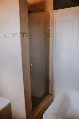 a shower with a glass door in a bathroom at White Linen Guesthouse in Tierpoort