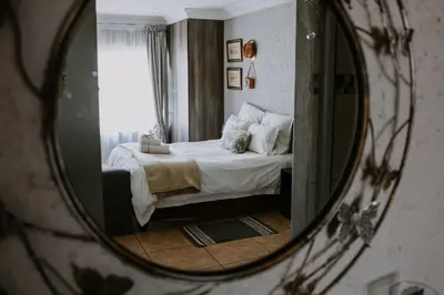 a reflection of a bedroom with a bed in a mirror at White Linen Guesthouse in Tierpoort