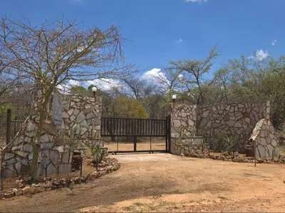 a stone fence with a gate and a tree at Kigeni Safari Lodge & Spa in Vaalwater