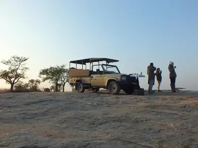 a group of people standing around a jeep in the desert at Rhino Post Safari Lodge in Skukuza