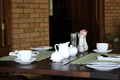 a wooden table with white cups and plates on it at Dreamfields Guesthouse in Hazyview