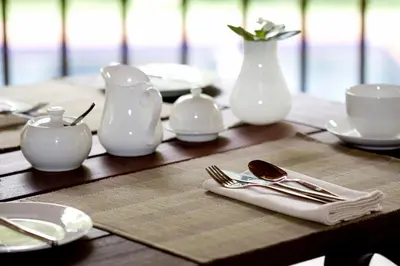 a wooden table with plates and utensils and a white vase at Dreamfields Guesthouse in Hazyview