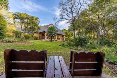 two wooden benches sitting in front of a house at Dreamfields Guesthouse in Hazyview