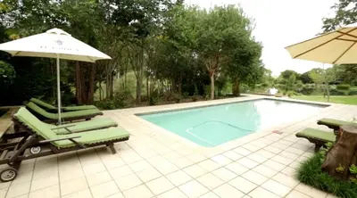 a swimming pool with lounge chairs and an umbrella at Oxbow Country Estate in Erasmus