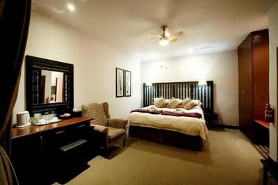 a bedroom with a bed and a chair and a mirror at Oxbow Country Estate in Erasmus