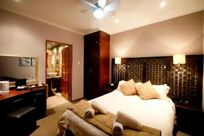a hotel room with a bed and a desk and a bathroom at Oxbow Country Estate in Erasmus