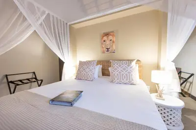 a bedroom with a large bed with a white bedspread at Bushbaby River Lodge in Hoedspruit