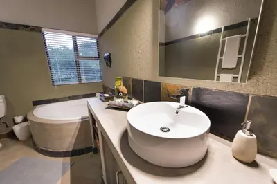 a bathroom with a sink and a tub and a toilet at Bushbaby River Lodge in Hoedspruit