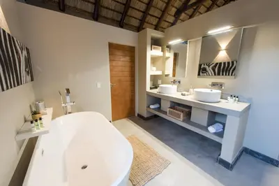 a bathroom with two sinks and a white tub at Bushbaby River Lodge in Hoedspruit