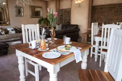 a living room with a table with plates and flowers on it at Our Heritage Guesthouse in Kempton Park