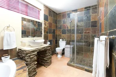 a bathroom with a toilet and a sink and a shower at Our Heritage Guesthouse in Kempton Park