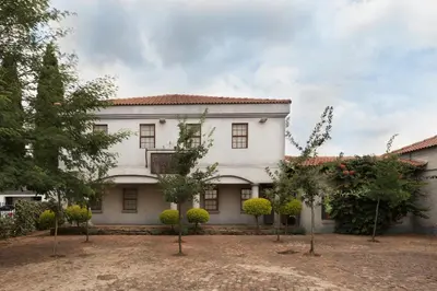 a large white house with trees in front of it at Our Heritage Guesthouse in Kempton Park