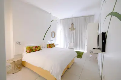 a white bedroom with a large bed with flowers on it at Alpine Attitude Boutique Hotel & Conference Venue in Pretoria
