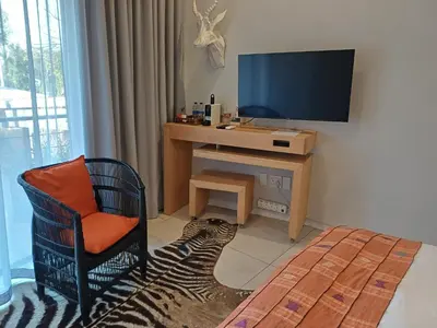 a room with a desk with a television and a chair at Alpine Attitude Boutique Hotel & Conference Venue in Pretoria