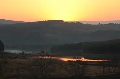 a sunset over a body of water with the sun setting at Klipkopje Guest Cottage in White River