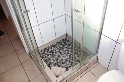 a shower with a glass door and a shower floor at Klipkopje Guest Cottage in White River