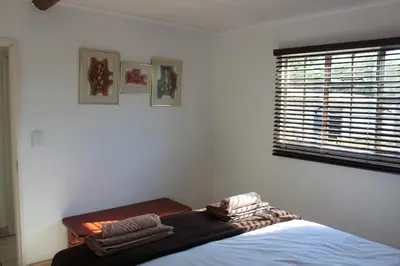 a bedroom with a bed and a window and towels at Klipkopje Guest Cottage in White River