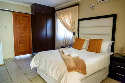 a bedroom with a large white bed with orange pillows at Hlulani Guest House in Northam