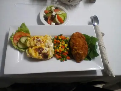 a plate of food with meat and vegetables on a table at Hlulani Guest House in Northam