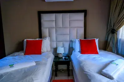 two beds with red pillows in a room at Hlulani Guest House in Northam