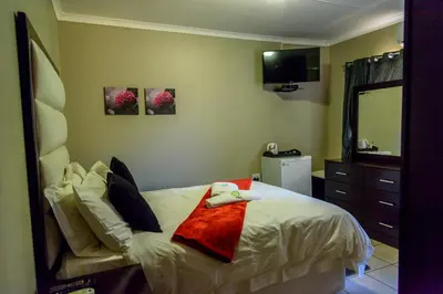 a bedroom with a bed with a mirror and a dresser at Hlulani Guest House in Northam
