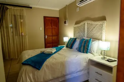 a bedroom with a white bed with blue pillows at Hlulani Guest House in Northam