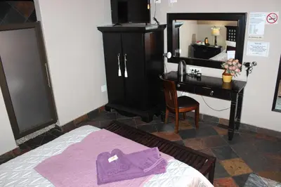 a bedroom with a bed with a vanity and a desk at Royal Game Guest House in Phalaborwa