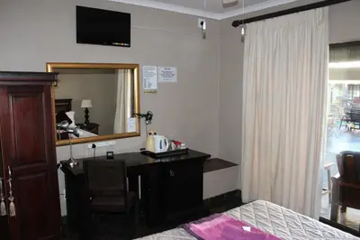 a hotel room with a desk and a mirror at Royal Game Guest House in Phalaborwa