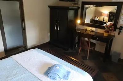 a bedroom with a bed and a desk and a mirror at Royal Game Guest House in Phalaborwa