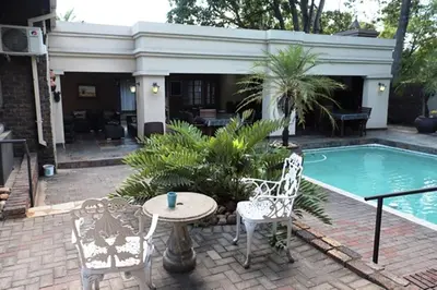 a patio with a table and chairs next to a pool at Royal Game Guest House in Phalaborwa